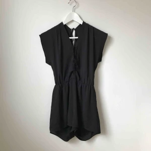  - Svart jumpsuit med snörning både framtill och baktill. Knappt använd. Köparen står för fraktkostnad enligt postens portotabell.