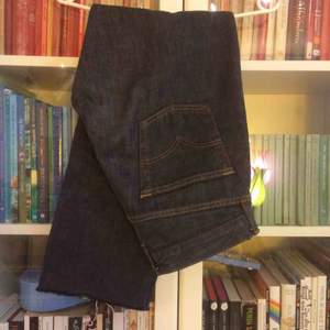 Ett par mörk blågråa Levi’s jeans med knappar i stället för gylf, väldigt bra skick med rough cut i byxben slutet
