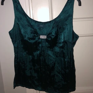 Grönblått linne! - Jättegulligt glansigt linne med en liten silverdetalj. Köpt second hand! Används inte så mycket därför säljer jag den, är i bra skick! Köparen står för frakt<3