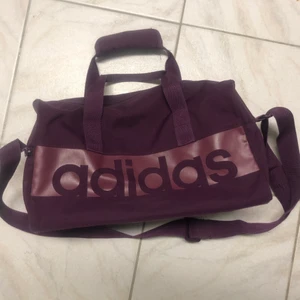 Lila adidasväska - Lila adidasväska som knappt är använd. Cirka 30cm på längden, 20cm bred och 15cm djup. (Egna mått med linjal så inte riktigt säkert) Jättefint skick. Köpt för 250kr och säljer för 100kr💞 Kund står för frakt