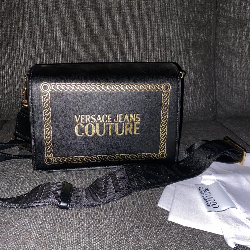 Väska från Versace med dustbag. Finns tre fack, två större och ett mindre. Fick den i julklapp 2019 av mitt ex och har bara använt den en gång, sagda dag, så väskan är i nyskick. Väskor.