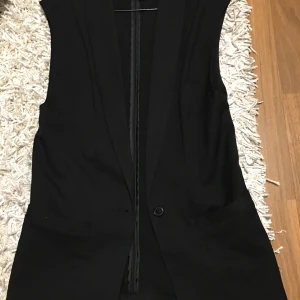 Svart väst  - Svart väst från H&m. Anv endast en gång, precis som ny. Säljer av en massa kläder som jag endast anv 1 gång lr aldrig pga ingen plats i garderoben. Snygg öppen som stängd. Knäpps med en knapp framtill. BUD på denna!. Fraktalternativ kan diskuteras. 