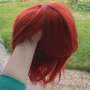  - Röd peruk, aldrig använd, finns hackar i båda kanter där man kan justera storlek. Fint skick,kommer med en perukpåse. Köpt från coscraft för mer än 200kr. Frakt är inte inkluderat men priset går att diskutera.