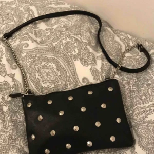  - Svart liten väska med nitar på. (18x13cm)