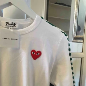  - Vit långärmad Comme des garçon med rött hjärta. I något använt men bra skick. Sitter som en S/XS. Skriv för fler bilder vid intresse. Frakt tillkommer
