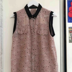  - Genomskinlig skjorta med flamingos på! Svart krage och lite guld/kopparfärgade knappar. Den har också ett öppet parti på ryggen. SÅ fin med en söt bh eller liknande under. Från märket Atmosphere.