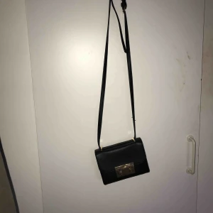  - Svart handväska med gulddetaljer! Har en iPhone 7+ och den får plats. Köparen står för frakten 