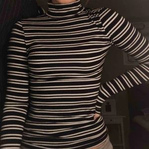  - Svart- och vitrandig polotröja från Gina Tricot. Strechig i materialet med kroppsnära passform i storlek S. ALDRIG använd och i NYTT skick!