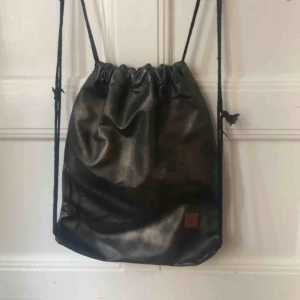  - Klassisk ”gympapåse” i faux-läder.  Mörkgrå med lätt skimmer. 