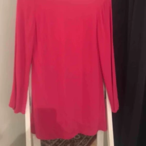  - En tunnare klänning men urringning i bak.  Klänningen är rosa, ej åt det röda hållet