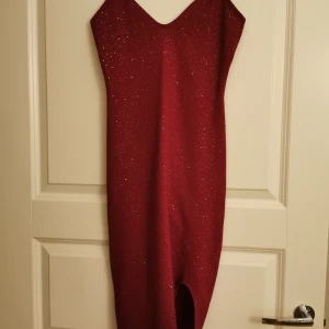  - Fin röd klänning med glitter i sig. Slits vid ena benet och formar sig vid rumpan. I fint skick,använd 1 gång. Storlek S 