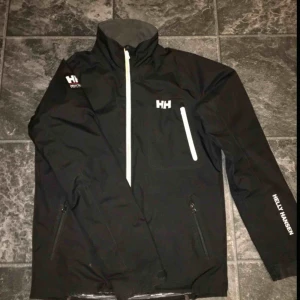  - Helly Hansen vindjacka för män , strl S , nästan helt oanvänd .  Bästa skicket och fraktas med bildbevis . Nypris ca 1300.