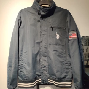  - Marinblå jacka från US Polo association, köpt i USA för ett par år sedan och välanvänd men ändå i bra skick. Skickas med skicka lätt eller mötas upp.