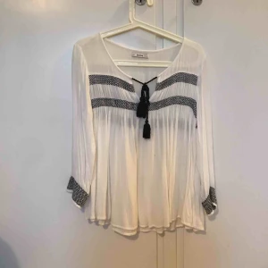  - Vit blus med band i fram. Använd men i gott skick. Frakt tillkommer 