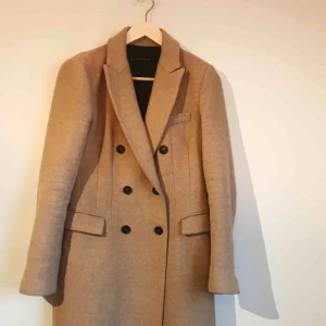  - Kamelfärgad höstkappa med knappar. Figursydd, smiter åt något runt midjan. Nypris ca 1400.