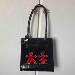  - Svart skinnvästs med rött motiv på både fram och baksidan. Knappt använd