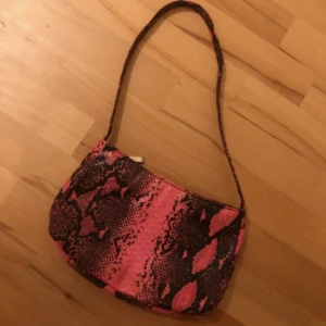  - Svinball schockrosa snakeprint väska i något glansigt tyg💖Köpt secondhand här, och verkligen oneofakind! Säljes pga att den inte fått komma till användning! Fint vintageskick! Är uppe i flytt så köp innan slutet av OKT. Om det finns ngt mer av intresse! Tillägg 30:- för frakt för denna så står jag för resten! 