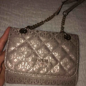  - Säljer min GUESS väska i en gammalrosa färg med guldiga detaljer, färgen har släppt lite på bokstäverna i fram men det syns knappt!💕 väl använd men fint skick. Köparen står för halva frakten annars mötas runt bromma