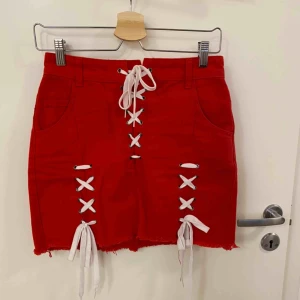 Kjol med snörning - Streetstyle jeanskjol med fickor både fram och bak. Snörning längs kjolen samt i midjan för perfekt passform o justering. Små fransar längst ner av kjolen 