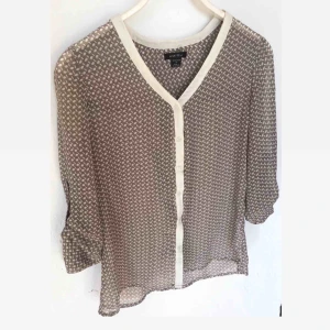  - Beige blus med vita prickar. Tyget är av transparens karaktär. Ger en söt look. Välbevarad. 