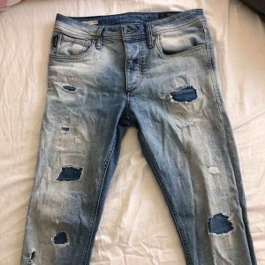  - Ljusblåa jeans från jack and Jones i storlek 30-32. Har slitna detaljer längs benen