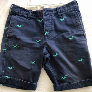  - Mörkblåa Hollister shorts med grön/turkosa detaljer i storlek 28. 