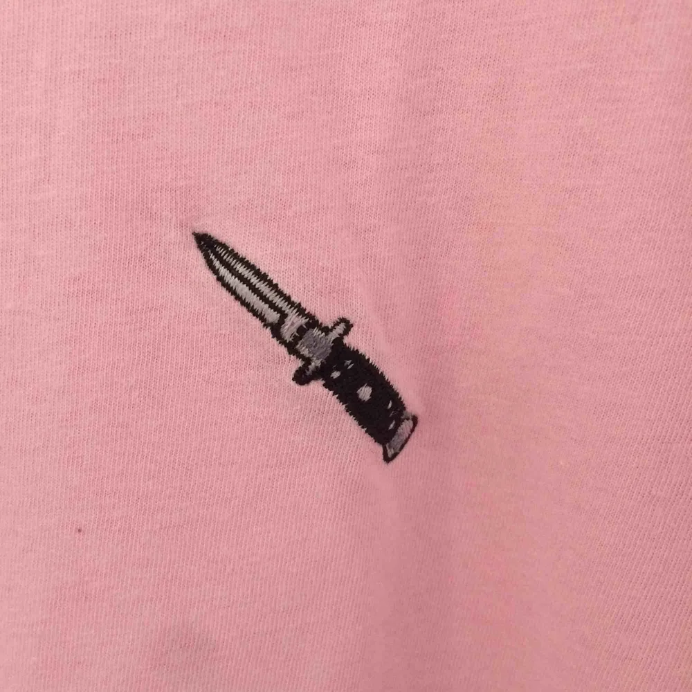 Rosa T-shirt från urban outfitters. Använd endast ett fåtal gånger. Broderad kniv på bröstet. 100kr + frakt 🥰. T-shirts.