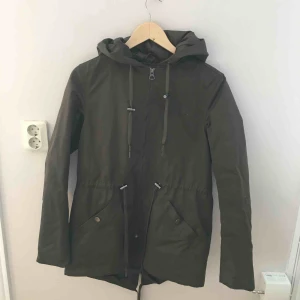  - Lårlång parkas i mörkgrönt. Passar såväl på stan som ute i skogen! 🌳