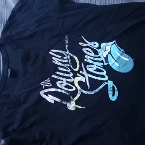 Rolling stones t-shirt - Rolling Stones t-shirt med mesh över bröstet, bild två. Sitter inte på ett sätt så brösten syns på mig, 173cm lång. Tröjan är i perfekt skick då den är använd några få gånger bara.