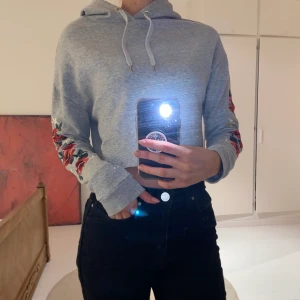 Crop top med fina broderingar - Säljer nu vidare min fina crop top med så fina broderingar på armarna🤍 Hoodien har en luva och snören & är i storlek xs men passar mig som är en S🥰 Den är använd men är som i nyskick så jag använd den försiktigt💓