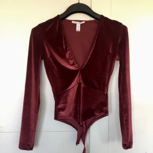  - Body i sammetsliknande tyg från Nelly. Använd 1 gång. Knäppning i gren, och djup v-ringning.