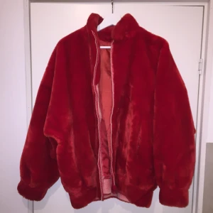  - Röd fuskpäls jacka. Innefoder något skadat, annars fint skick!