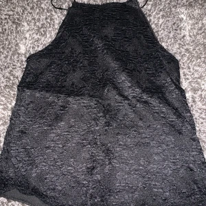 Fint svart spetslinne. - Framsidan av spets har en baksida av ett svart tyg, men baksidan av linnet är bara spets.