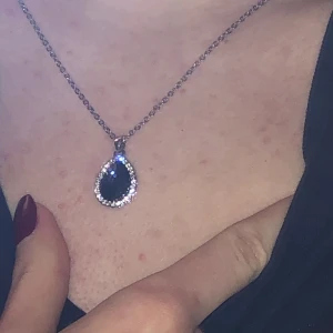 Halsband - Silverfärgat halsband med blå ”päronformad” berlock knappt använd. 