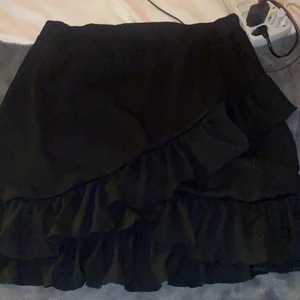 Kjol - Svart kjol med en volang från Nelly, aldrig använd storlek L (frakt tillkommer)
