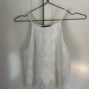 Virkad, vit topp från BikBok - Virkad, vit topp från BikBok i strl. S som har några år på nacken. Gott skick förutom en tidigare lagning av axelbandet! Slutar lite nedanför midjan, så passar bra till högmidjade jeans. Säljer för 50 kr, fraktkostnad tillkommer och kan anpassas beroende på vikt och önskemål!