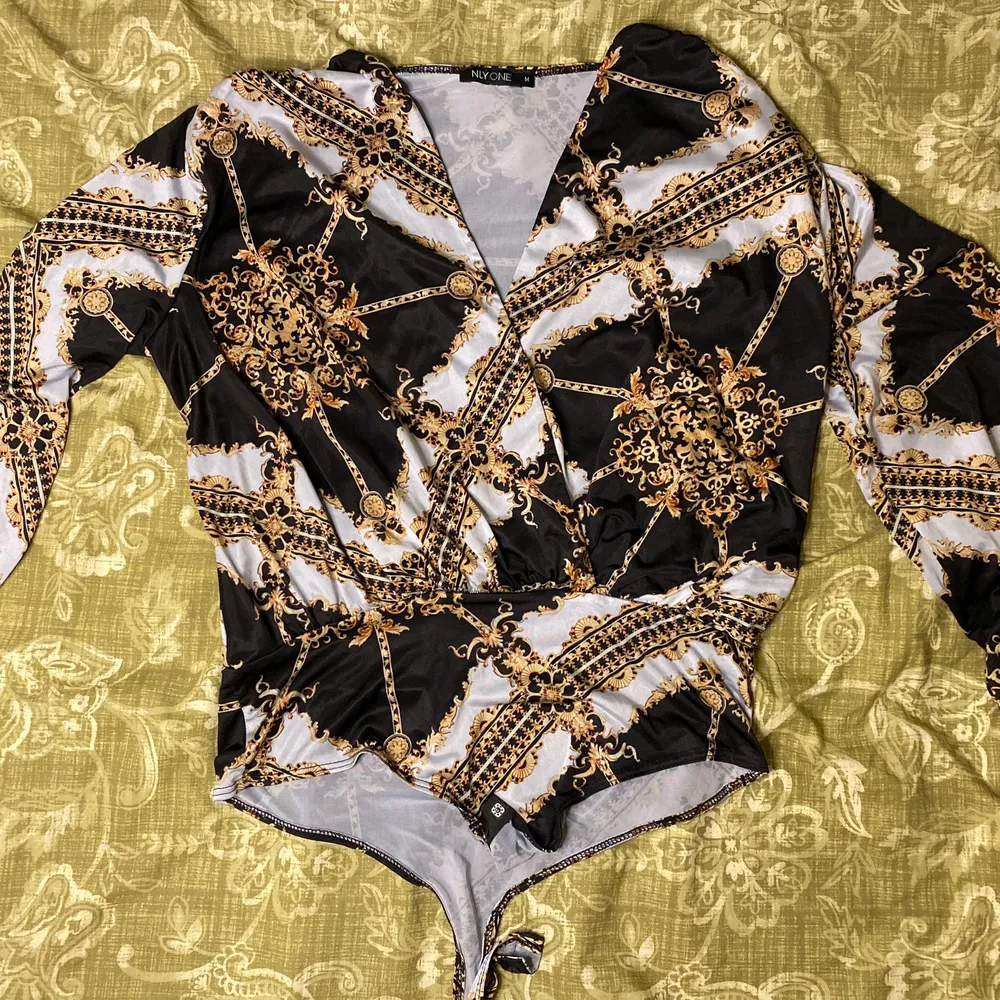 En wrap bodysuit med väldigt classy mönster i vitt, svart och gult. Materialet är jätte lent och silkig. I nytt skick. . Blusar.