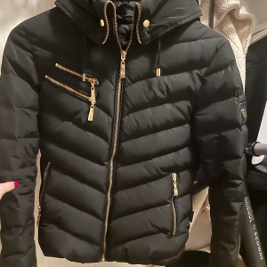 Hollies chatel jacka  - Svart Hollies chatel jacka med guld detaljer. Inköpt för ca två år sedan på johnells för 5000:-. Inga skavanker och den är i väldigt bra skick! Kan skicka med pälsen (äkta) om man vill. 