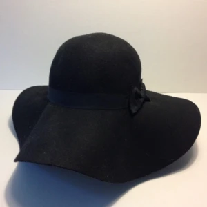  - Fin svart slokhatt i filt. Dekorativ rosettdetalj i sidan. 