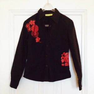  - Svart formsydd skjorta / blus med blodrött asymmetriskt tryck på bröstet och sidan.  FRI FRAKT!