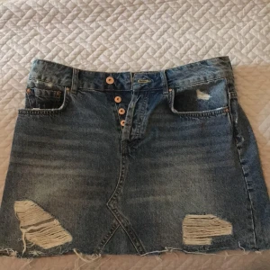 Jeanskjol från Zara storlek M - Snygg jeanskjol från Zara med flera knappar och lite ripped. I nytt skick då den är knappast använd. Storlek M. 