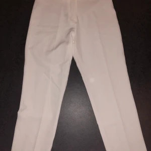 Kostymbyxor (oanvända)  - Helt oanvända vita kostymbyxor som har prislappen kvar. Storlek 12 som motsvar M/L