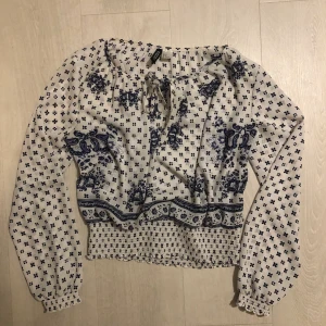 Vitblå blus - Vit blus med blått mönster från H&M. Resår längst ner och i slutet på ärmarna. 🤪 70kr + frakt 
