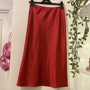 Röd satinkjol från Topshop - Röd midikjol i satin/siden från topshop! I storlek 38 men skulle säga att den passar 36 också🥰 Frakt tillkommer!❤️