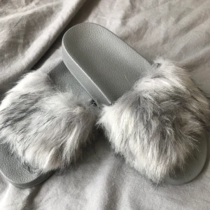 Fluffiga tofflor - Fluffiga gråa tofflor köpta på EBay för 300kr. Använda utomhus 2 gånger. Storlek 36, men passar även större. 