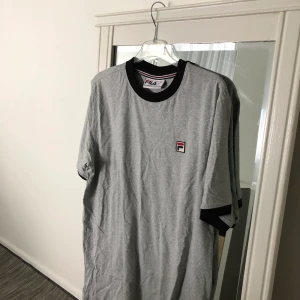 Fila t-shirt - En äkta grå fila t-shirt i storlek S (man storlek). Rätt lång i storleken. Ganska ny och aldrig använt. Frakt förekommer, men kan mötas i Göteborg. För fler frågor och bilder kontakta mig!