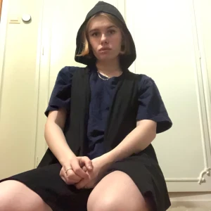 Svart väst med luva - En svart väst med luva i storlek L/XL men passar som en M som max. Den har en liten ficka på vänstra nedre sidan. Den är längre fram och är V-ringad där så det ser lite ut som spetsar, skriv för mer bilder.