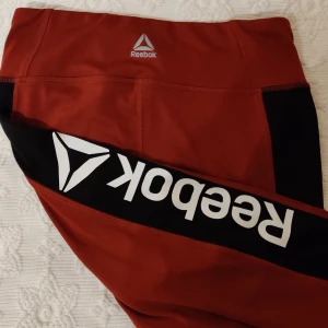 Reebok träningstights S - Röda träningstights från Reebok Storlek S Endast använda en gång. Bortklippt lapp Inga slitningar på trycket.  Fraktförslag mottages gärna. Samfraktar.
