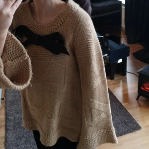 Stickad tröja  - Stickad tröja ifrån märket Malene Birger. Beige med en mörkgrå rosett. 