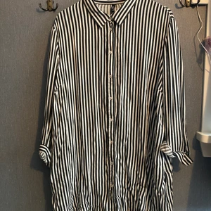 Skjorta - Vit och svart randig skjorta. Då den är i storlek 2xl så blir den väldigt oversized mer som en skjortklänning på mig som vanligtvis har Stl. M/L . Väldigt skön. 
